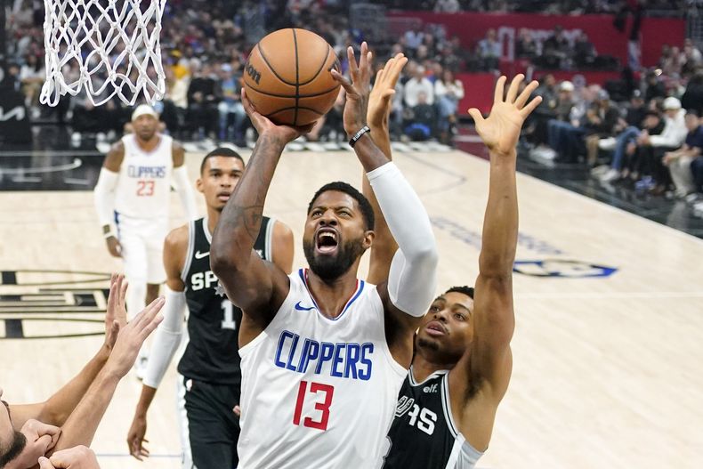 El alero de los Clippers de Los Ángeles Paul George lanza el balón a la canasta frente al alero de los Spurs de San Antonio Keldon Johnson en el encuentro del domingo 29 de octubre del 2023 en Los Ángeles. (AP Foto/Mark J. Terrill)