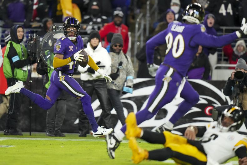El quarterback de los Steelers de Pittsburgh, Russell Wilson, abajo a la derecha, golpea el césped mientras el esquinero de los Ravens de Baltimore, Marlon Humphrey, a la izquierda, devuelve una intercepción para touchdown durante la segunda mitad el sábado 21 de diciembre de 2024, en Baltimore. (AP Foto/Stephanie Scarbrough)