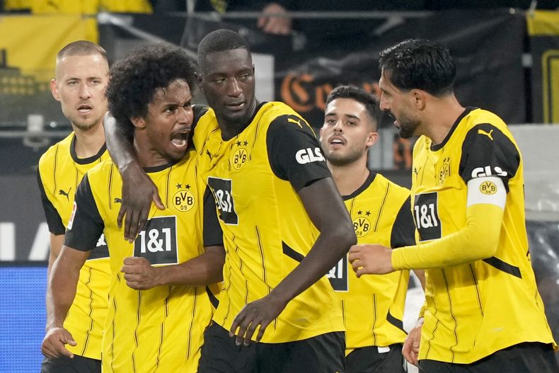 Serhou Guirassy, del Dortmund, celebra junto a sus compañeros de equipo, Karim Adeyemi (2do desde la izquierda), y Emre Can (derecha), tras anotar el tercer gol de su equipo en el partido de la Liga de Alemania, ante el Bochum, en Westfalenstadion en Dortmund, Alemania, el viernes 27 de septiembre de 2024. (AP FotoMartin Meissner)