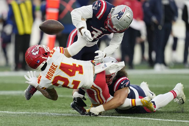Skyy Moore, receptor de los Chiefs de Kansas City, es derribado por Jonathan Jones (arriba) y Jahlani Tavai, de los Patriots de Nueva Inglaterra, en el partido del domingo 17 de diciembre de 2023 (AP Foto/Charles Krupa)