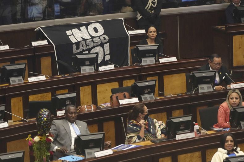Los legisladores de la oposición se sientan cerca de un cartel que dice ¡No Lasso, no! mientras la Asamblea Nacional celebra una sesión para decidir si continúa el proceso que podría conducir a la destitución del presidente Guillermo Lasso, acusado de presunta malversación de fondos públicos, en Quito, Ecuador, el martes 9 de mayo de 2023. (AP Foto/Dolores Ochoa)