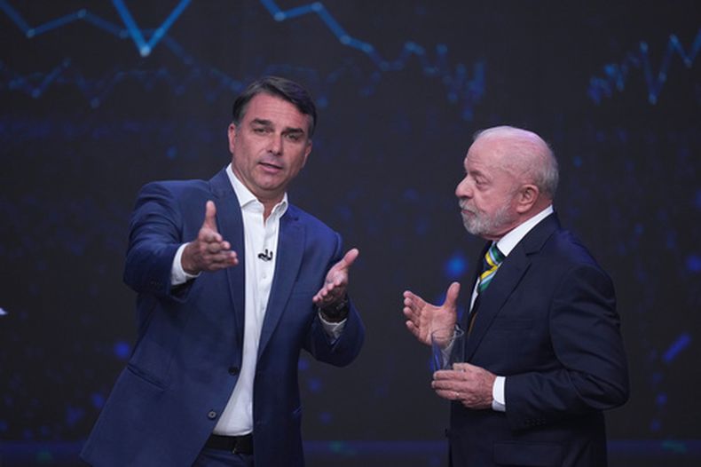 El senador Flavio Bolsonaro, candidato presidencial opositor --a la izquierda--, ofrece una explicación mientras lo observa el presidente brasileño Luiz Inácio Lula da Silva, que aspira a la reelección, durante un debate presidencial televisado una semana antes de la segunda vuelta electoral, el domingo 18 de octubre de 2026, en Sao Paulo, Brasil. (AP Foto/André Penner)