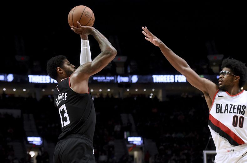 Paul George, izquierda, alero de los Clippers de Los Ángeles, dispara sobre Scoot Henderson, de los Trail Blazers de Portland, durante la segunda mitad del juego de baloncesto de la NBA, en Portland, Oregon, el viernes 22 de marzo de 2024. (AP Foto/Steve Dykes)