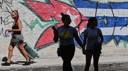 Varias mujeres pasan junto a grafitis con los colores de la bandera cubana, el miércoles 17 de junio de 2026, en La Habana, Cuba. (AP Foto/Jorge Luis Baños)