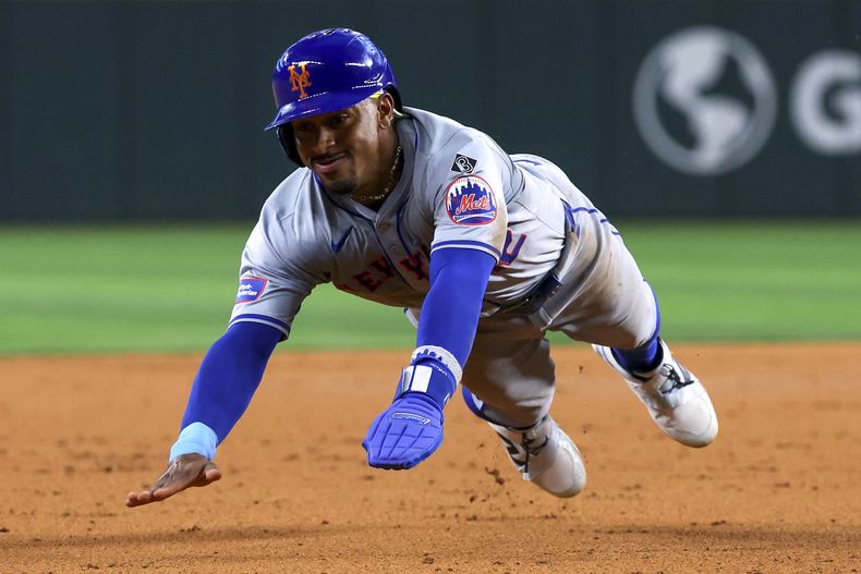 Francisco Lindor, de los Mets de Nueva York, se barre en tercera en la segunda entrada del juego de béisbol en contra de los Rangers de Texas el lunes 17 de junio de 2024, en Arlington, Texas. (AP Foto/Richard W. Rodriguez)