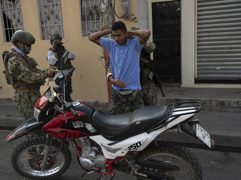 Soldados cachean a un conductor de moto e inspeccionan su documentación en un puesto de control en Durán, ubicada frente a Guayaquil, Ecuador, el 28 de septiembre de 2023. (AP Foto/Rodrigo Abd)