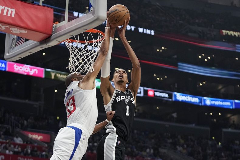 El pívot de los Spurs de San Antonio Victor Wembanyama lanza el balón sobre el alero de los Clippers de Los Ángeles Nicolas Batum en el encuentro del domingo 29 de octubre del 2023. (AP Foto/Mark J. Terrill)