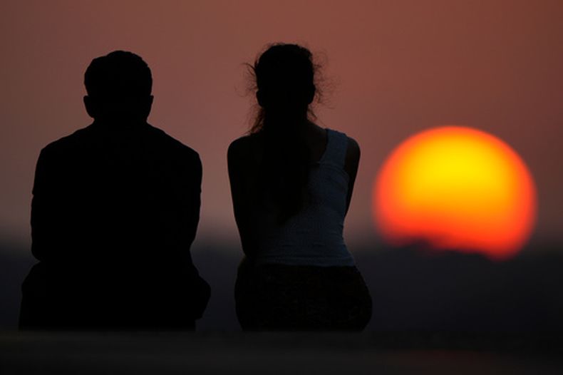 La gente observa la puesta de sol al final de un caluroso día de verano, el 26 de julio de 2026, en Kansas City, Misuri. (AP Photo/Charlie Riedel)