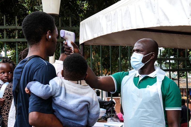 Un funcionario de salud utiliza un termómetro para tomar la temperatura a las personas frente al Hospital Musulmán de Kibuli, en Kampala, Uganda, el sábado 16 de mayo de 2026. (AP Foto/Hajarah Nalwadda)