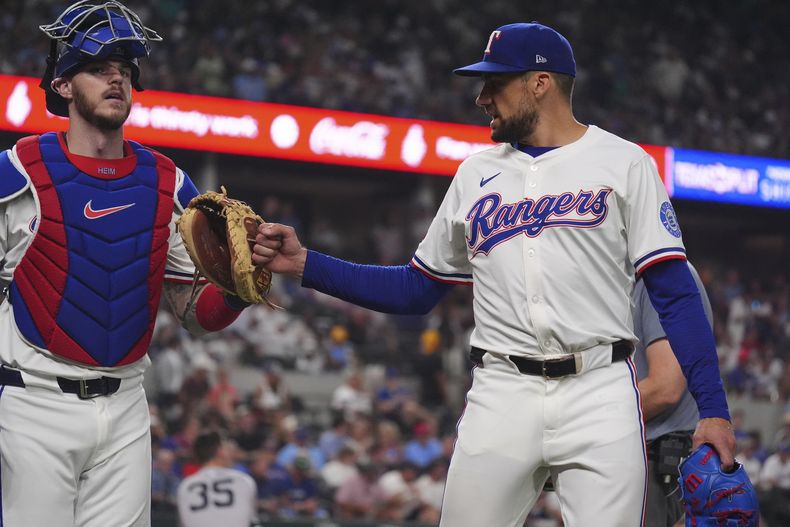 El abridor de los Rangers de Texas Nathan Eovaldi saluda al catcher Jonah Heim tras el tercer out en la cuarta entrada ante los Yankees de Nueva York el martes 5 de agosto del 2025. (AP Foto/LM Otero)