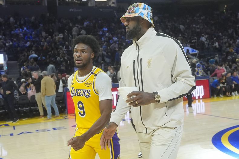 El escolta de los Lakers de Los Ángeles, Bronny James (9), sale de la cancha con LeBron James durante el medio tiempo de un partido de baloncesto de pretemporada de la NBA contra los Warriors de Golden State en San Francisco, el viernes 18 de octubre de 2024. (AP Foto/Jeff Chiu)