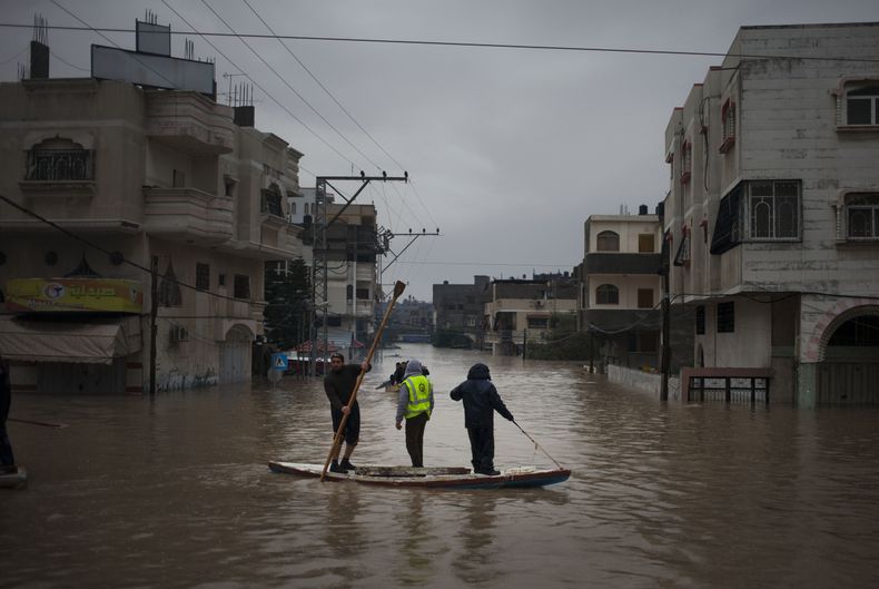 Socorristas palestinos ayudan a habitantes a evacuar una zona inundada por las fuertes lluvias en la Ciudad de Gaza, el s&aacute;bado 14 de diciembre de 2013. La Franja de Gaza recibi&oacute; su primer env&iacute;o de combustible industrial en 45 d&iacute