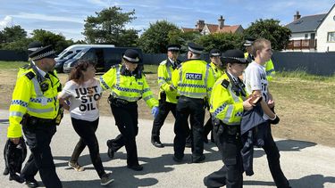 Manifestantes de Just Stop Oil son escoltados por la policía en el hoyo 17 después de que lanzaron un material naranja al campo en el Abierto Británico el viernes 21 de julio del 2023. (AP Foto)