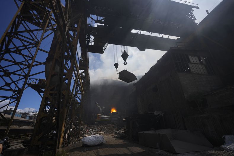 Una grúa levanta un contenedor lleno de armas incautadas para ser destruidas en una planta metalúrgica en Nobsa, Colombia, el jueves 5 de diciembre de 2024. (Foto AP/Fernando Vergara)