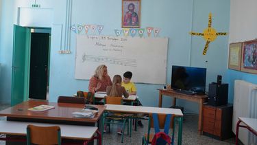 La maestra Chryssa Ntalaka enseña música a dos estudiantes de la escuela primaria Kalamos, incluido Gerasimos Mitsopoulos, de 11 años, a al derecha, en la isla de Kalamos en el mar Jónico, en el oeste de Grecia, el miércoles 23 de septiembre de 2026. (AP Foto/Petros Giannakouris)