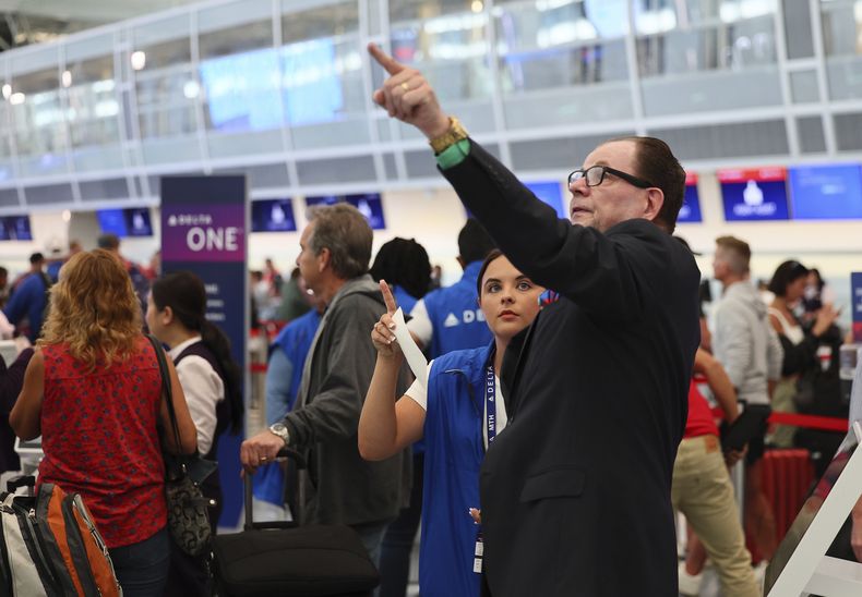 Empleados de servicio al cliente de la aerolínea Delta dan información a viajeros de vuelos retrasados mientras hacen fila en el aeropuerto Internacional Minneapolis/St. Paul luego que una actualización de software defectuosa causó estragos tecnológicos en todo el mundo, el viernes 19 de julio de 2024, en Minneapolis. (AP Foto/Adam Bettcher)