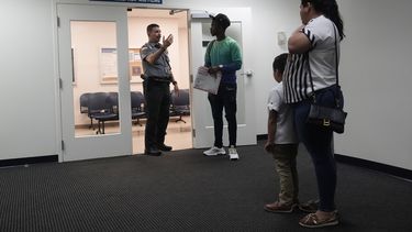 Un oficial ayuda a un grupo de personas en un tribunal de inmigración en Miami, el 10 de enero de 2024.. (Foto AP/Wilfredo Lee)