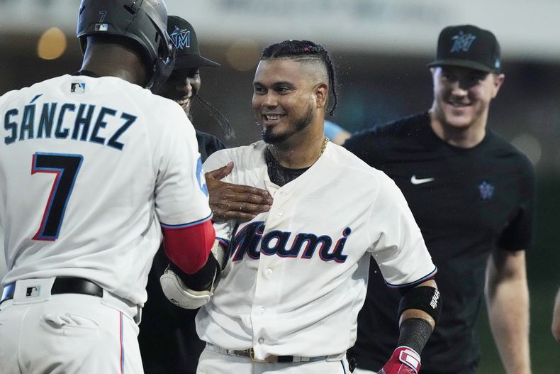 Luis Arráez (3), de los Marlins de Miami, es felicitado por sus compañeros de equipo después de producir la carrera de la victoria en el juego de béisbol en contra de los Rockies de Colorado, en 10 entradas, el domingo 23 de julio de 2023, en Miami. Los Marlins derrotaron 3-2 a los Rockies. (AP Foto/Marta Lavandier)