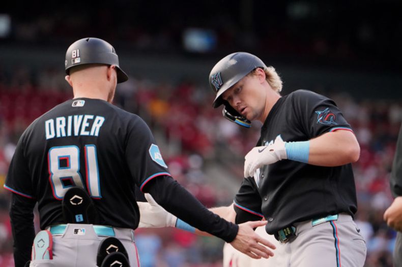 Kyle Stowers, derecha, de los Marlins de Miami, es felicitado por el coach de primera base, Craig Driver, después de batear un sencillo productor durante la primera entrada del juego de béisbol de Grandes Ligas contra los Cardenales de San Luis, el sábado 27 de junio de 2026, en San Luis. (AP Foto/Jeff Roberson)