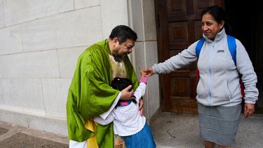 El padre Carlos Reyes saluda a los feligreses tras celebrar misa en el Santuario del Sagrado Corazón, una iglesia católica, el domingo 12 de octubre de 2025, en Washington. (AP Foto/Luis Andrés Henao)