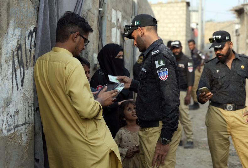 Policías paquistaníes realizan revisiones de identidad a un residente durante una campaña contra la inmigración no autorizada en un barrio de Karachi, Pakistán, el martes 21 de noviembre de 2023. (AP Foto/Fareed Khan)