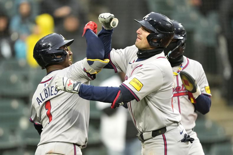 Austin Riley, derecha, de los Bravos de Atlanta, celebra con Ozzie Albies después de batear un cuadrangular de tres carreras frente al relevista de los Medias Blancas de Chicago, Dominic Leone, en la octava entrada del juego de béisbol de las mayores, el lunes 1 de abril de 2024, en Chicago. (AP Foto/Charles Rex Arbogast)