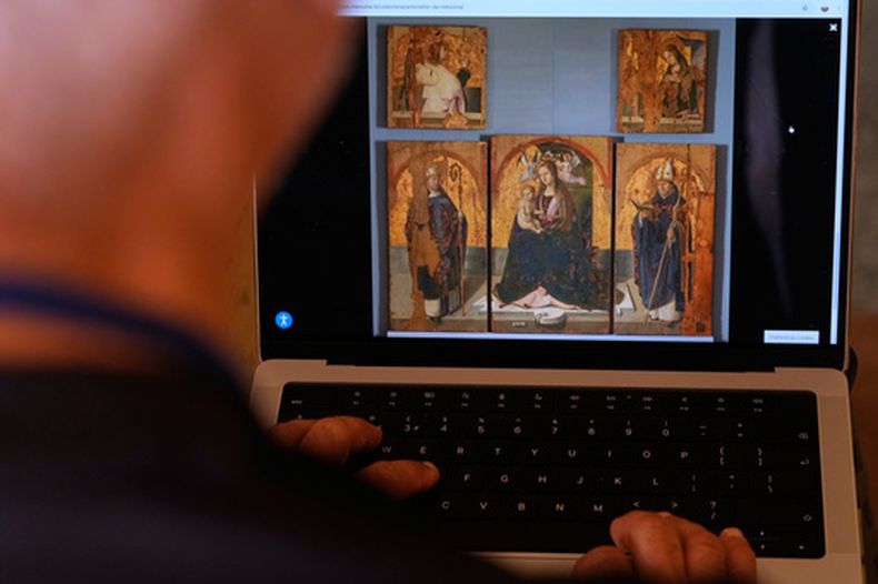 Un periodista mira el sitio web del museo de Messina, que muestra una imagen de una obra del pintor renacentista Antonello da Messina, en la que tres de los cinco paneles forman el políptico de San Gregorio, y una tabla con doble cara con la Virgen y el Cristo en Piedad, robados del museo siciliano el 15 de agosto en Roma, el domingo 16 de agosto de 2026. (AP Foto/Gregorio Borgia)