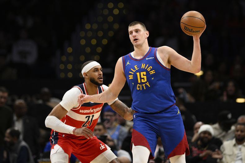 El centro de los Nuggets de Denver Nikola Jokić (15) sostiene el balón ante el pívot de los Wizards de Washington Daniel Gafford, durante la primera mitad del juego de baloncesto de la NBA, el domingo 21 de enero de 2024, en Washington. (AP Foto/Nick Wass)