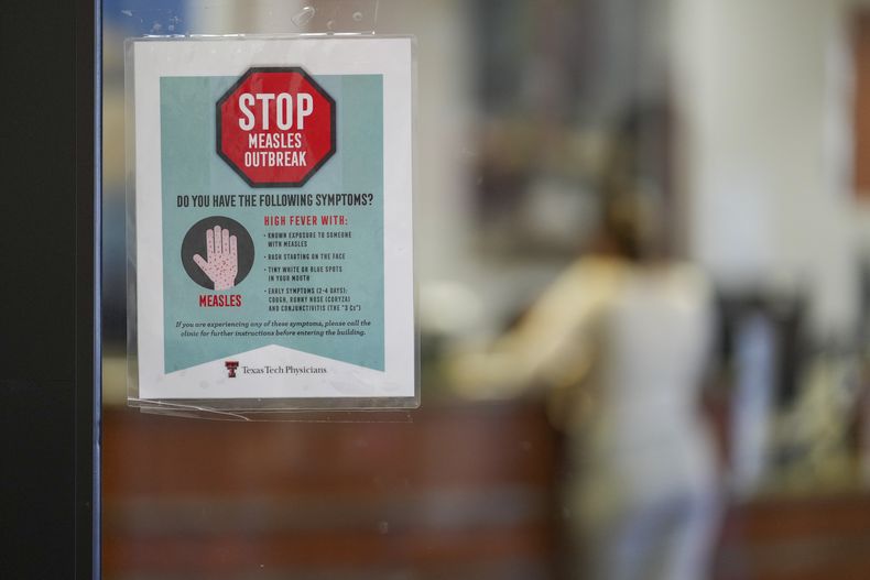 Un letrero de advertencia sobre el sarampión en una puerta de cristal, mientras una paciente llega a una cita en el área de medicina familiar en Texas Tech Physicians of the Permian Basin, el lunes 24 de febrero de 2025, en Odessa, Texas. (AP Foto/Julio Cortez)