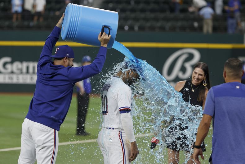 El venezolano Martín Pérez vacía la hielera sobre el dominicano Ezequiel Durán, su compañero de los Rangers de Texas, quienes vencieron el martes 2 de mayo de 2023 a los Diamondbacks de Arizona (AP Foto/Michael Ainsworth)
