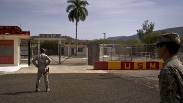 ARCHIVO - En esta fotografía revisada por oficiales militares de Estados Unidos, un soldado del ejército, derecha, y un miembro de la infantería de Marina permanecen frente a las verjas que separan el territorio cubano de la Base Naval estadounidense, el 6 de junio de 2018, en Bahía de Guantánamo, Cuba. (AP Foto/Ramón Espinosa, archivo)