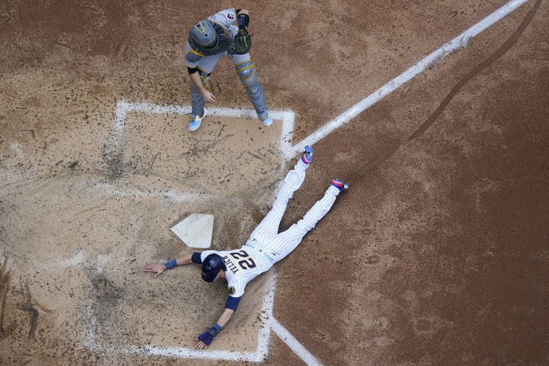 Christian Yelich de los Cerveceros de Milwaukee anota una carrera ante el receptor Jason Delay de los Piratas de Pittsburgh, el domingo 18 de julio de 2023, en Milwaukee. (AP Foto/Morry Gash)