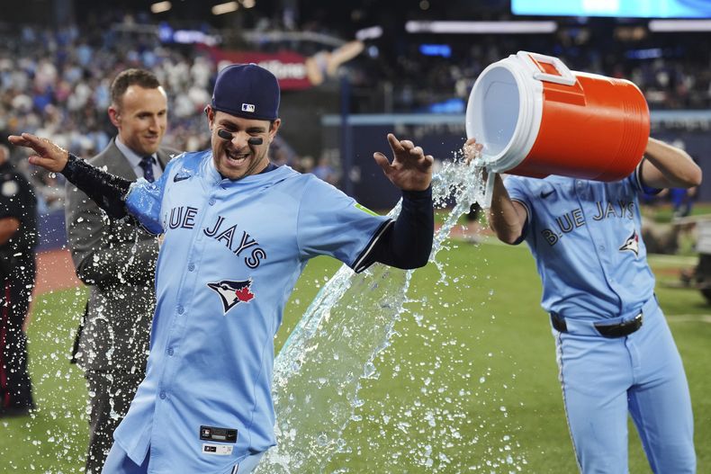 Ernie Clement de los Azulejos de Toronto bañado por sus compañeros tras superar a los Cachorros de Chicago el martes 12 de agosto del 2025. (Nathan Denette/The Canadian Press via AP)
