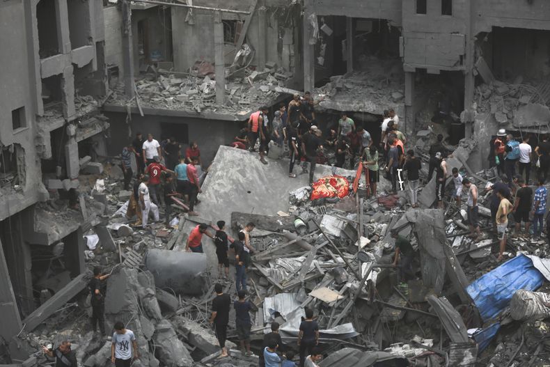 Palestinos inspeccionan los daños en edificios destruidos por ataques aéreos israelíes, en la Ciudad de Gaza, el 27 de octubre de 2023. (AP Foto/Abed Khaled)
