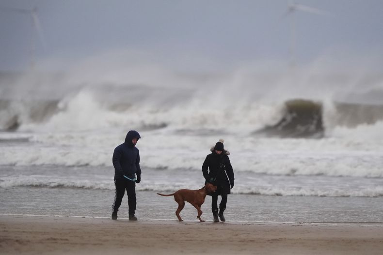 Una pareja pasea a sus perros en Tynemouth Longsandsm en la costa noreste de Newcastle, Inglaterra, el martes 31 de diciembre de 2024. (Owen Humphreys/PA vía AP)