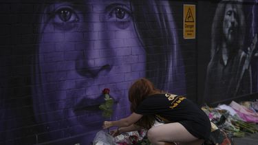 Una fan coloca una flor para conmemorar la muerte de Ozzy Osbourne en Birmingham, Inglaterra, el miércoles 23 de julio de 2025. (Foto AP/Kin Cheung)