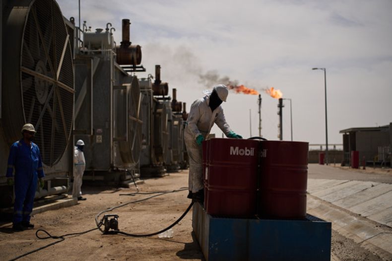 Un trabajador recoge aceite de motor mientras trabaja en una estación de desgasificación del yacimiento petrolífero de Zubair, cuyas operaciones se han reducido debido a la guerra en Oriente Medio provocado por los ataques de Estados Unidos e Israel contra Irán, cerca de Basora, Irak, el 28 de marzo de 2026. (AP Foto/Leo Correa)
