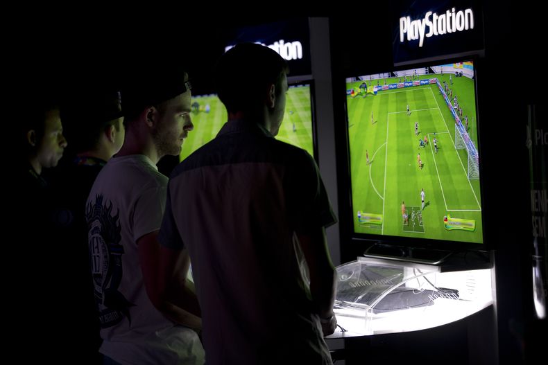 Un grupo de personas juega durante el Mundial Interactivo de la FIFA, en R&iacute;o de Janeiro, el jueves 3 de julio de 2014 (AP Foto/Silvia Izquierdo)