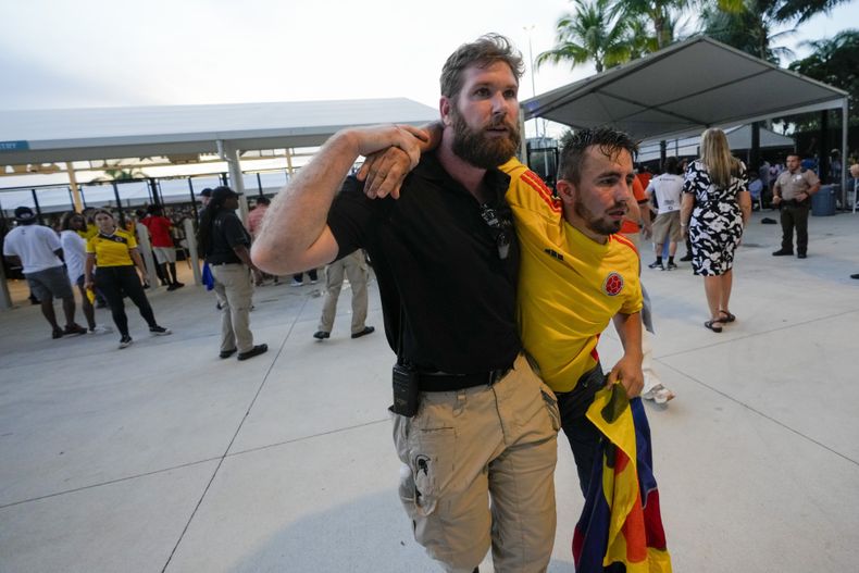 Un agente de seguridad asiste a un aficionado que esperaba entrar al estadio para la final de la Copa América entre Argentina y Colombia el domingo 14 de julio del 2024.(AP Foto/Lynne Sladky)
