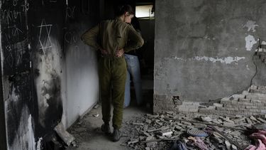 Una soldado israelí observa una casa marcada por la batalla en el kibutz Beeri, una granja comunal israelí en la frontera con Gaza, en el primer aniversario del ataque de Hamás contra Israel el lunes 7 de octubre de 2024. (AP Foto/Ohad Zwigenberg)