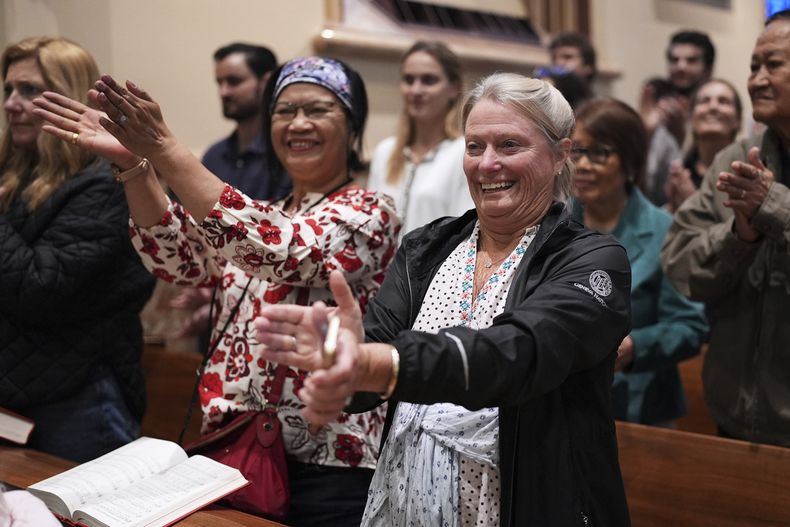 Victoria Bassig, izquierda, y Carolyn Smeltzer aplauden en honor del nuevo papa durante una misa en la catedral del Santo Nombre, el 11 de mayo de 2025, en Chicago. (AP Foto/Nam Y. Huh)