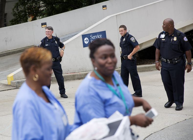 Empleadas de un hospital y polic&iacute;as vigilan una entrada al hospital de la Universidad de Emory en Atlanta, Georgia, tras el arribo de un estadounidense infectado con el virus &eacute;bola el 2 de agosto de 2014. Agentes federales en los aeropuertos