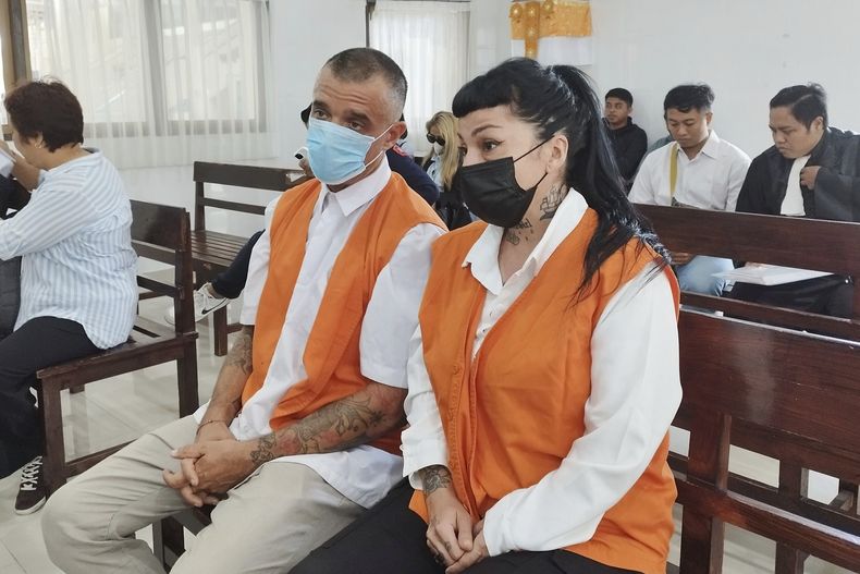 El ciudadano británico Elliot James Shaw, a la izquierda, y la ciudadana argentina Eleonora Gracia, a la derecha, que están acusados de llevar cocaína de contrabando a Indonesia, se sientan en la banca de los acusados al inicio de su juicio en Denpasar, Bali, el jueves 26 de junio de 2025. (AP Foto)