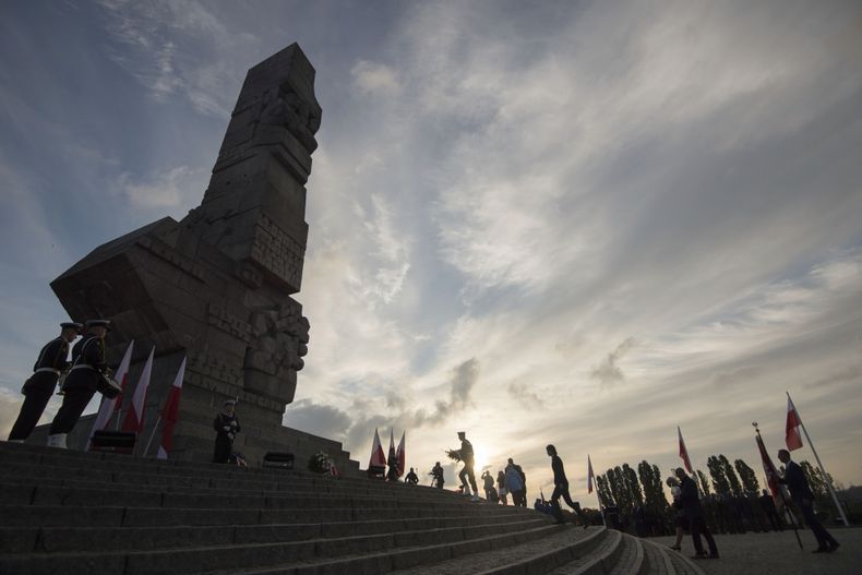 Personas colocan flores en un monumento a la defensa histórica de la península de Westerplatte en 1939 durante una ceremonia solemne por el 85to aniversario de la invasión nazi, el domingo 1 de septiembre de 2024, en Westerplatte, Polonia. (AP Foto/Wojciech Strozyk)