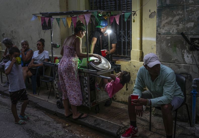 Una mujer compra sopa a un vendedor ambulante durante un corte de energía en La Habana, Cuba, el lunes 21 de octubre de 2024. (AP Foto/Ramón Espinosa)