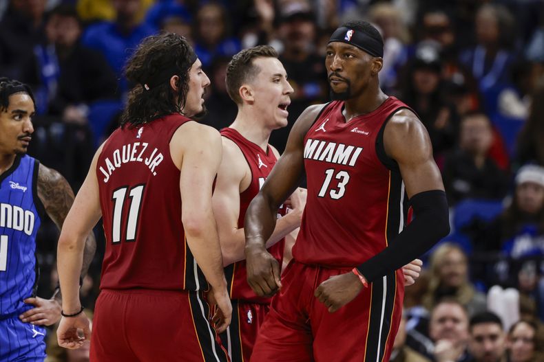 Bam Adebayo (13), pívot del Heat de Miami, festeja con sus compañeros, el mexicano Jaime Jáquez Jr., y el alero Duncan Robinson, durante el encuentro ante el Magic de Orlando, el miércoles 20 de diciembre de 2023 (AP Foto/Kevin Kolczynski)