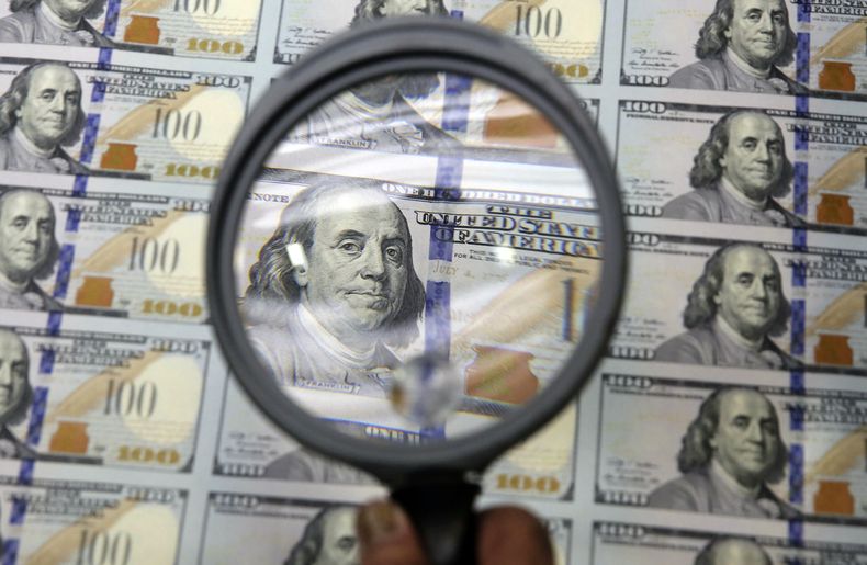 ARCHIVO - En esta foto del 24 de septiembre de 2014 alguien inspecciona una hoja con billetes impresos de 100 d&oacute;lares en una instalaci&oacute;n del gobierno en Fort Worth, Texas. El fortalecimiento de la econom&iacute;a estadounidense, combinado co