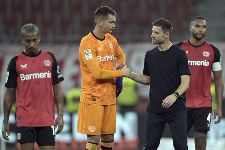 El brasileño Arthur (desde la izquierda) del Leverkusen, el portero Matej Kovar, el entrenador Xabi Alonso, y Jonathan Tah en la cacha luego del un partido de fútbol entre el Bayer Leverkusen y RB Leizig en el BayArena, en Leverkusen, Alemaniam el sábado 31 de agosto de 2024. (Federico Gambarini/dpa via AP)