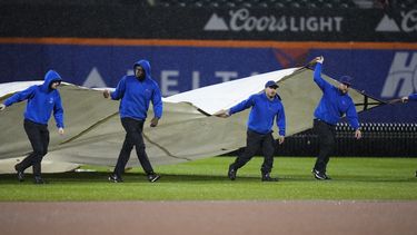 Empleados cubren el terreno de juego durante una suspensión por lluvia en el duelo entre los Mets de Nueva York y los Marlins de Miami, el viernes 29 de septiembre de 2023, en Nueva York. (AP Foto/Frank Franklin II)
