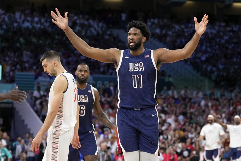 El estadounidense Joel Embiid tras recibir una falta del serbio Filip Petrusev en el baloncesto masculino de los Juegos Olímpicos de París, el domingo 28 de julio de 2024, en Villeneuve-dAscq, Francia. (AP Foto/Michael Conroy)